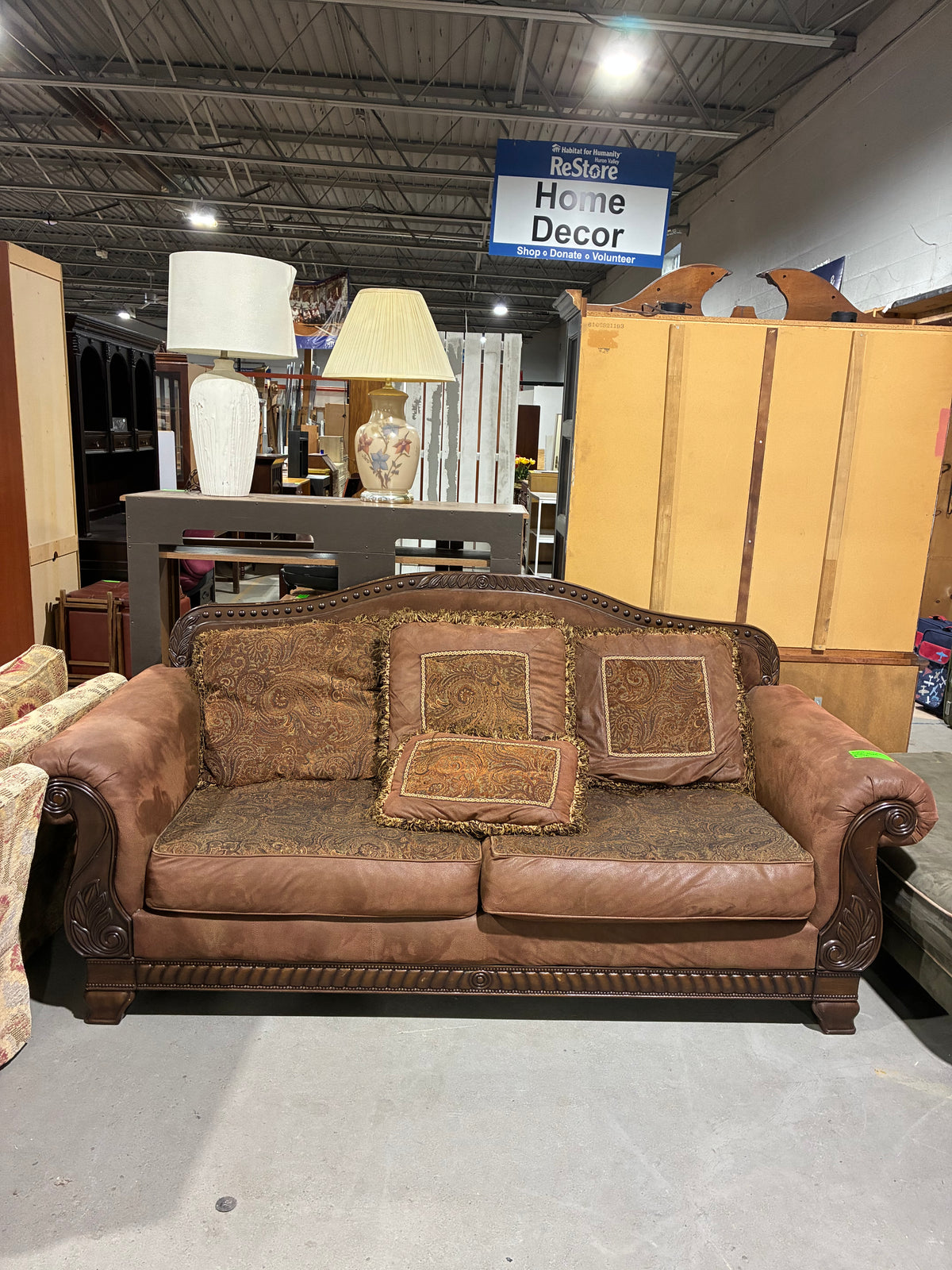 Traditional Brown Sofa with Ornate Carved Wood Accents & Paisley Cushions